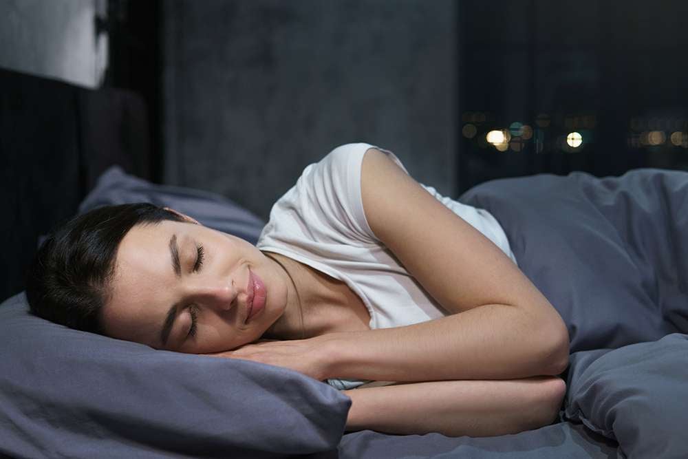 A graphic showing a woman sleeping in bed with a clock showing hours of sleep.