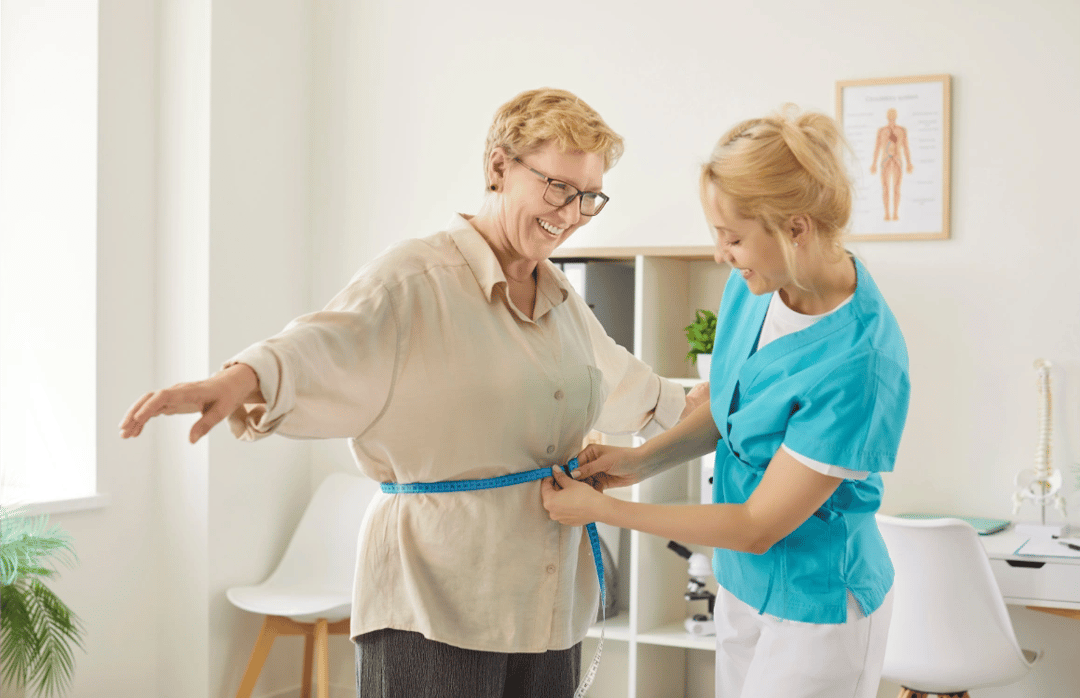 nurse measuring waist of smiling senior woman with tape