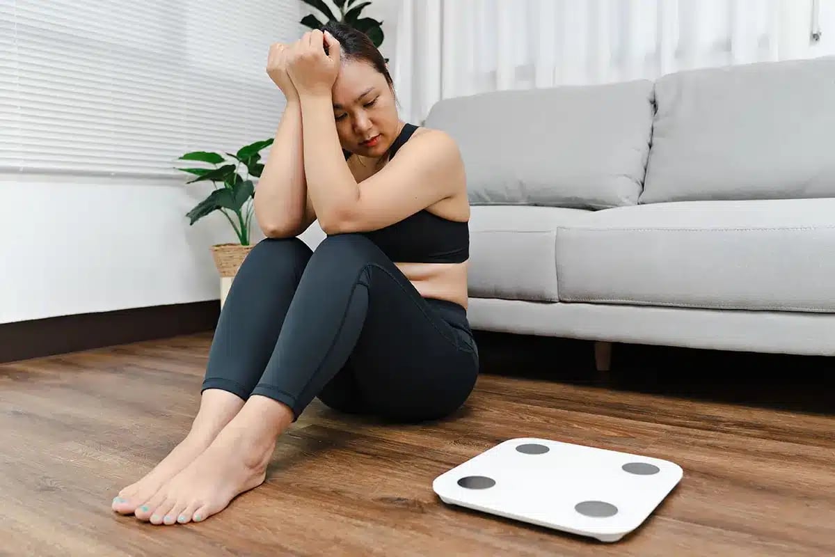 Woman feeling upset near weighing scales.