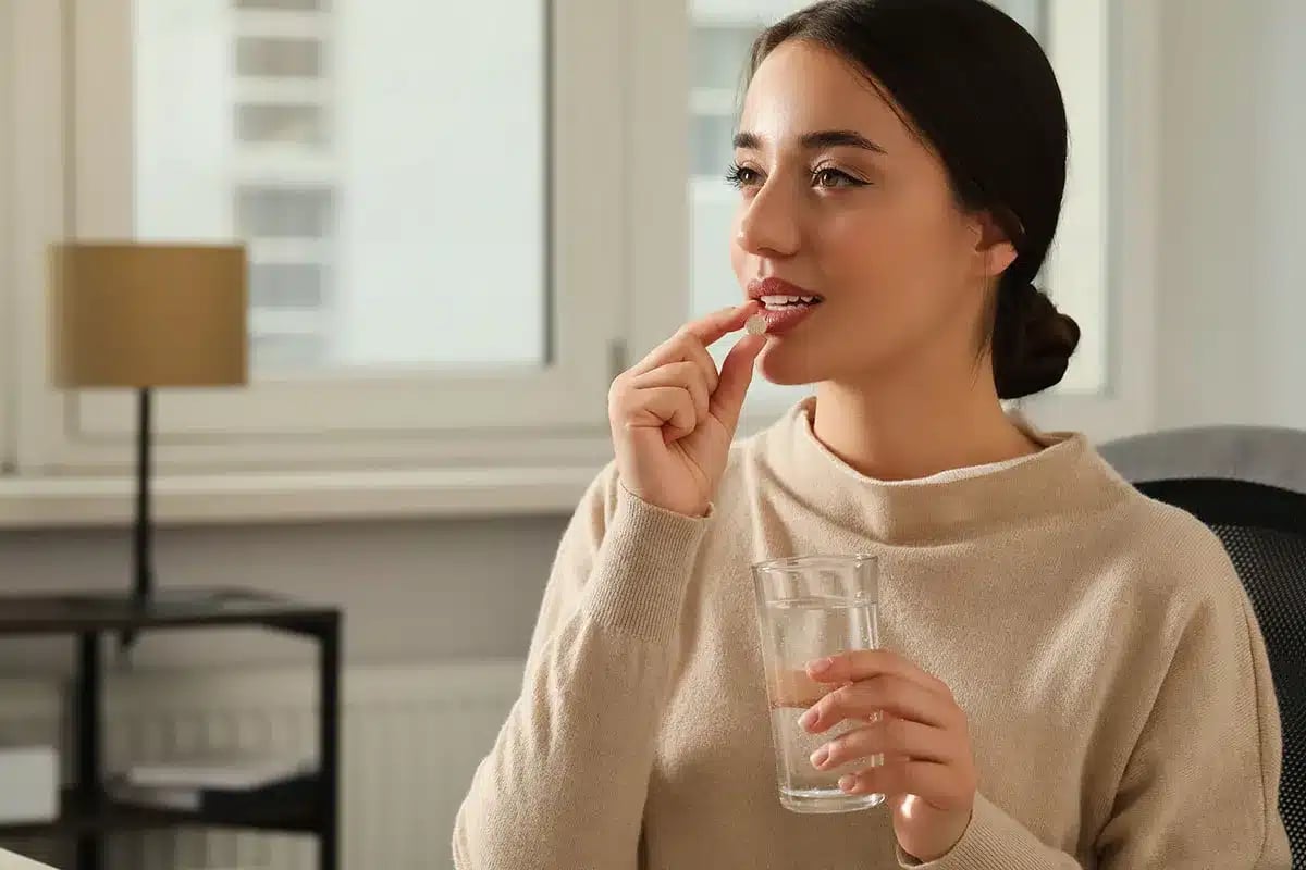 Woman taking medication with water.