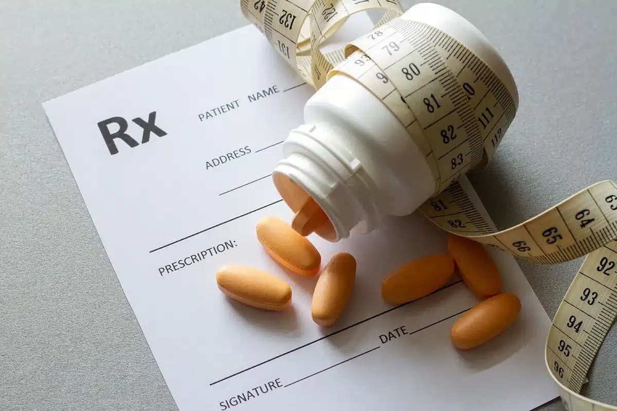 Prescription bottle and pills with measuring tape.