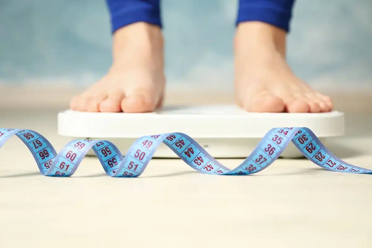 Feet on a scale with measuring tape.