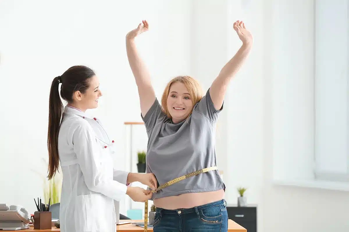 Doctor measuring a woman's waist.