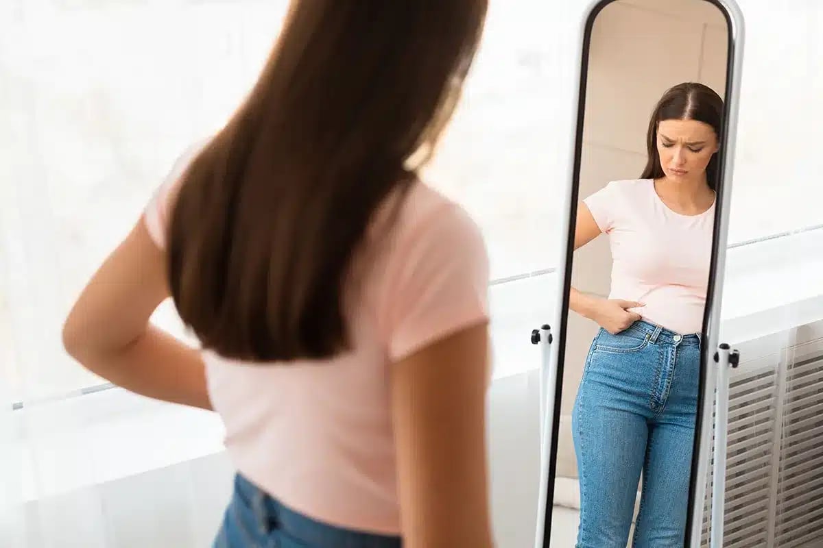 Woman looking at her reflection, unhappy.