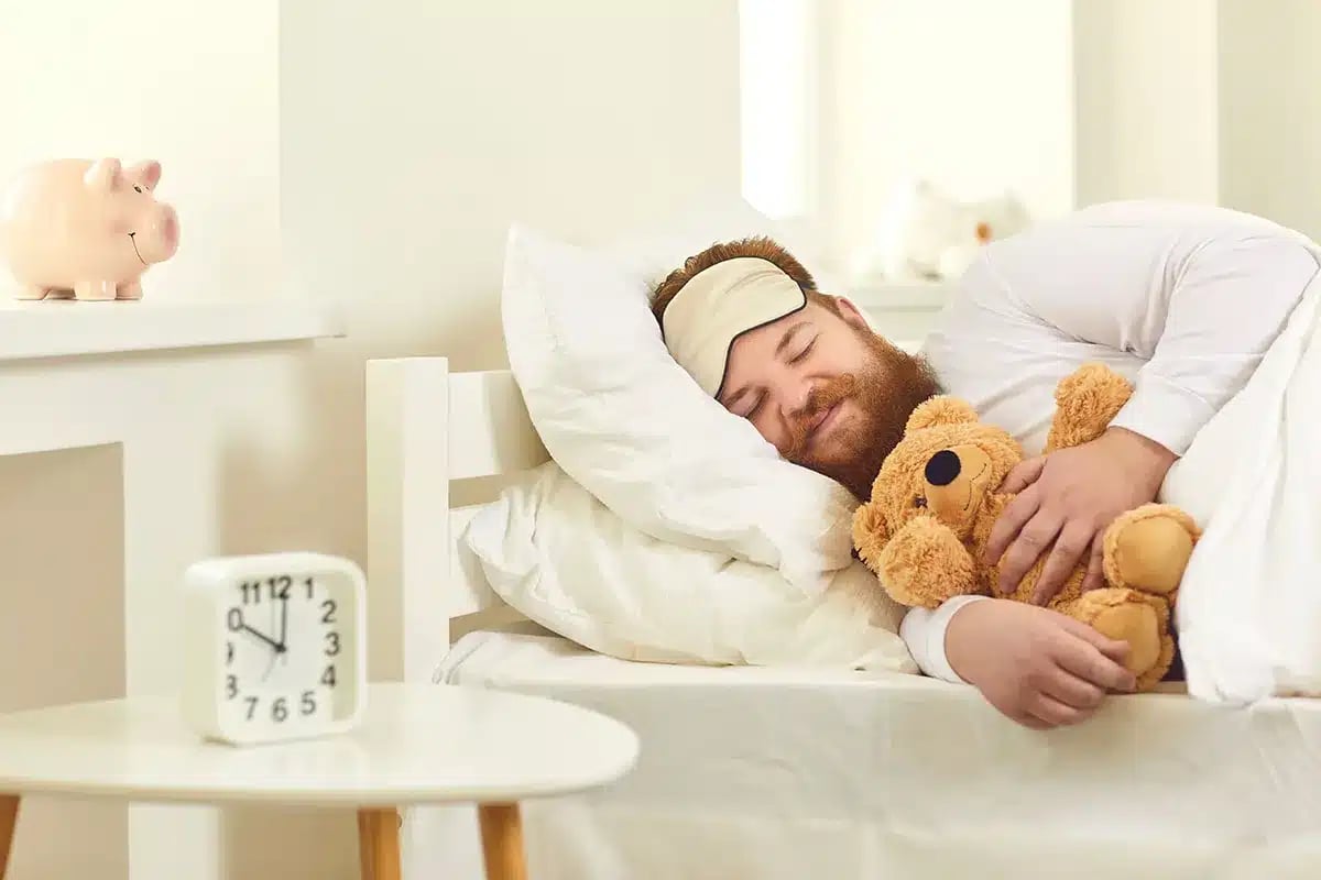 Man sleeping with teddy bear.