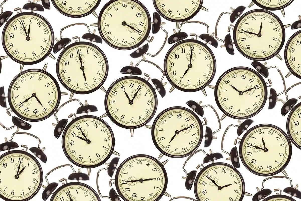 Many alarm clocks showing different times.