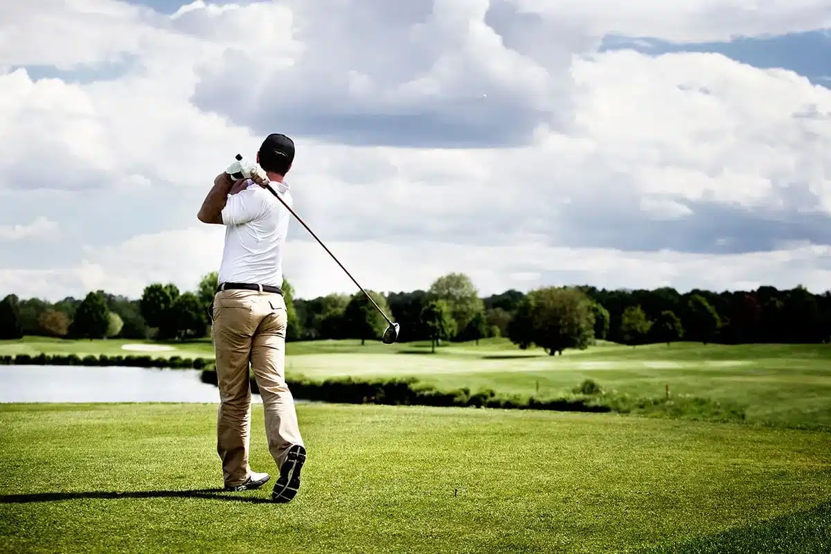 Golfer taking a swing on golf course.