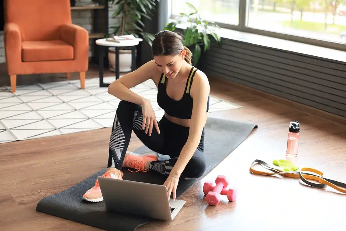 Woman following online fitness class at home.