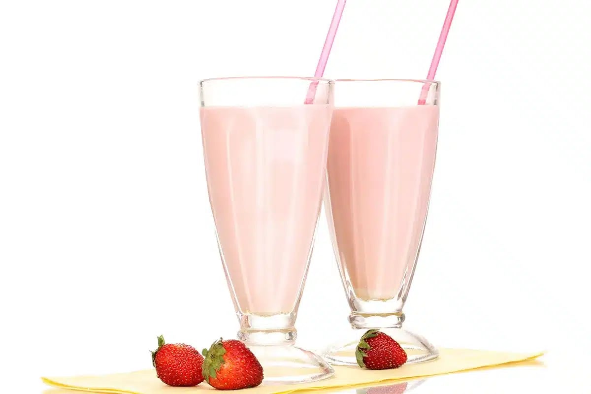 Two strawberry milkshakes with straws.