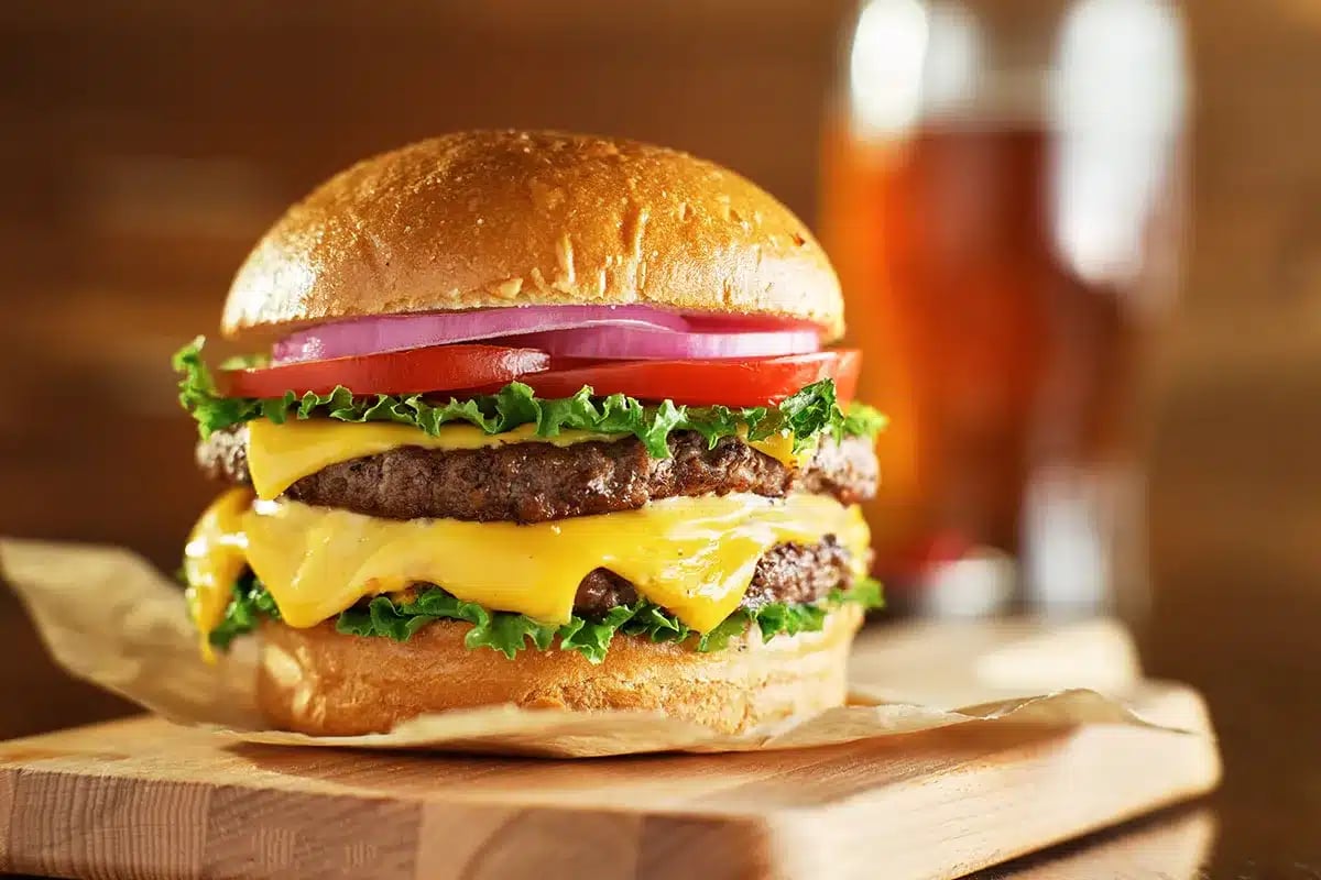 Juicy double cheeseburger on wooden board.