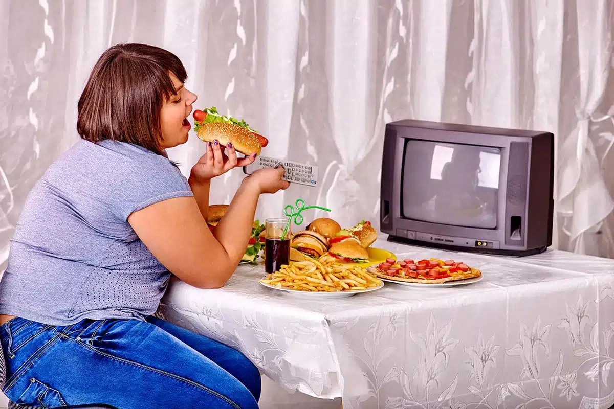Overweight woman eating junk food.
