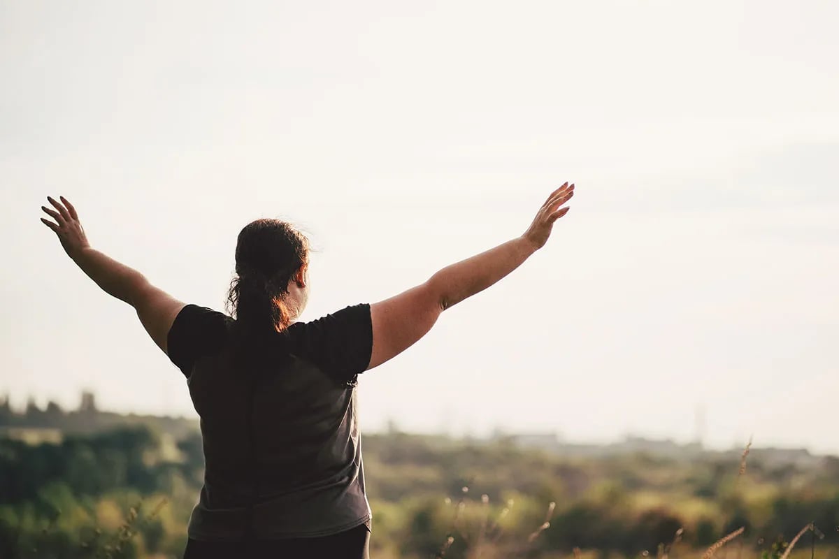Woman with arms outstretched, enjoying nature.
