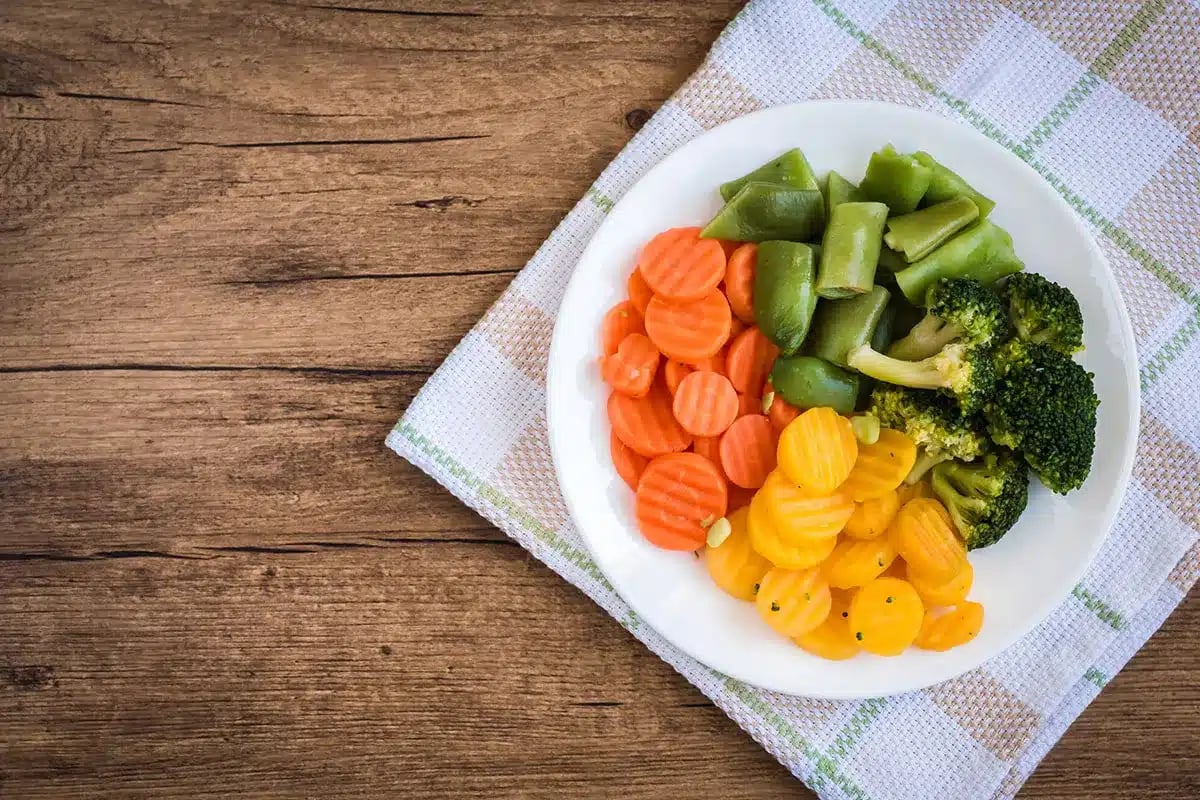 Plate of steamed carrots, broccoli, and green beans.