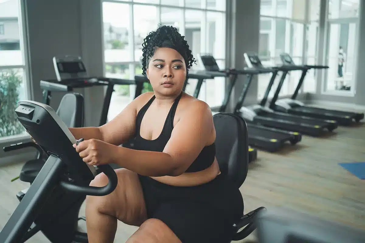 Plus-size woman exercising on stationary bike.