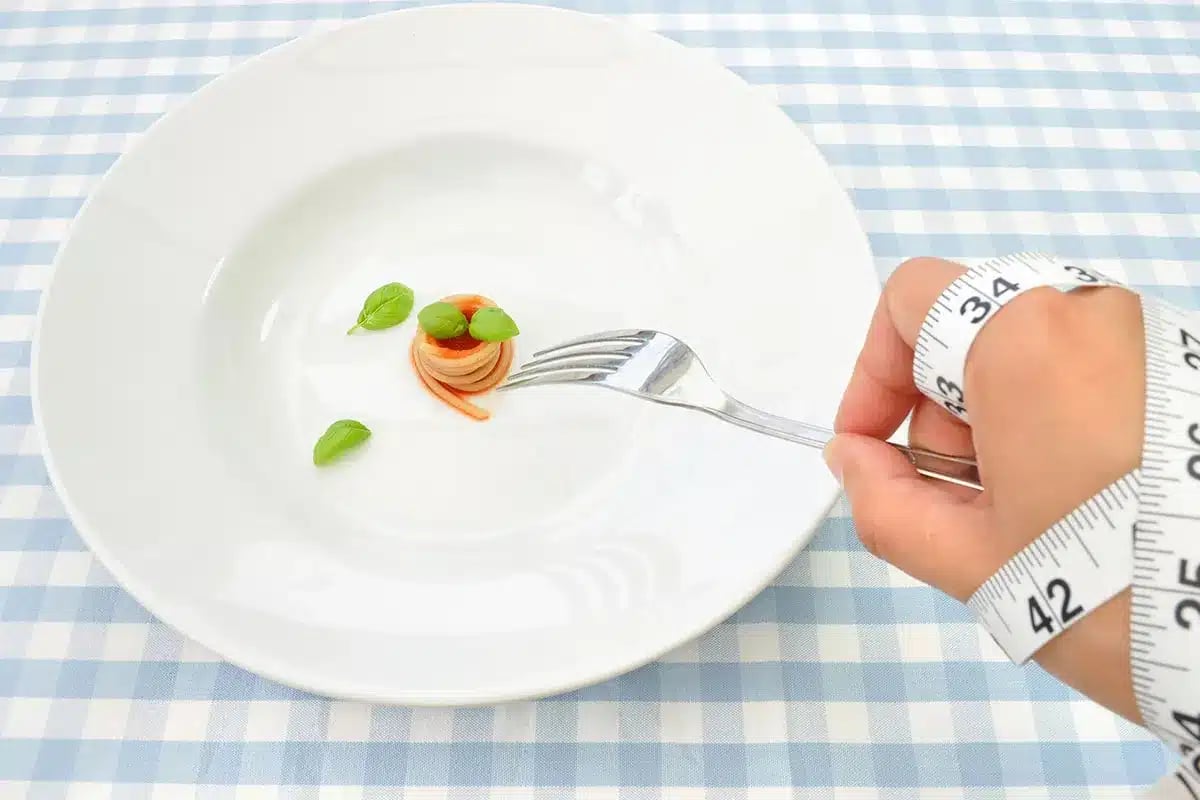 Small portion of pasta on a plate, measuring tape.