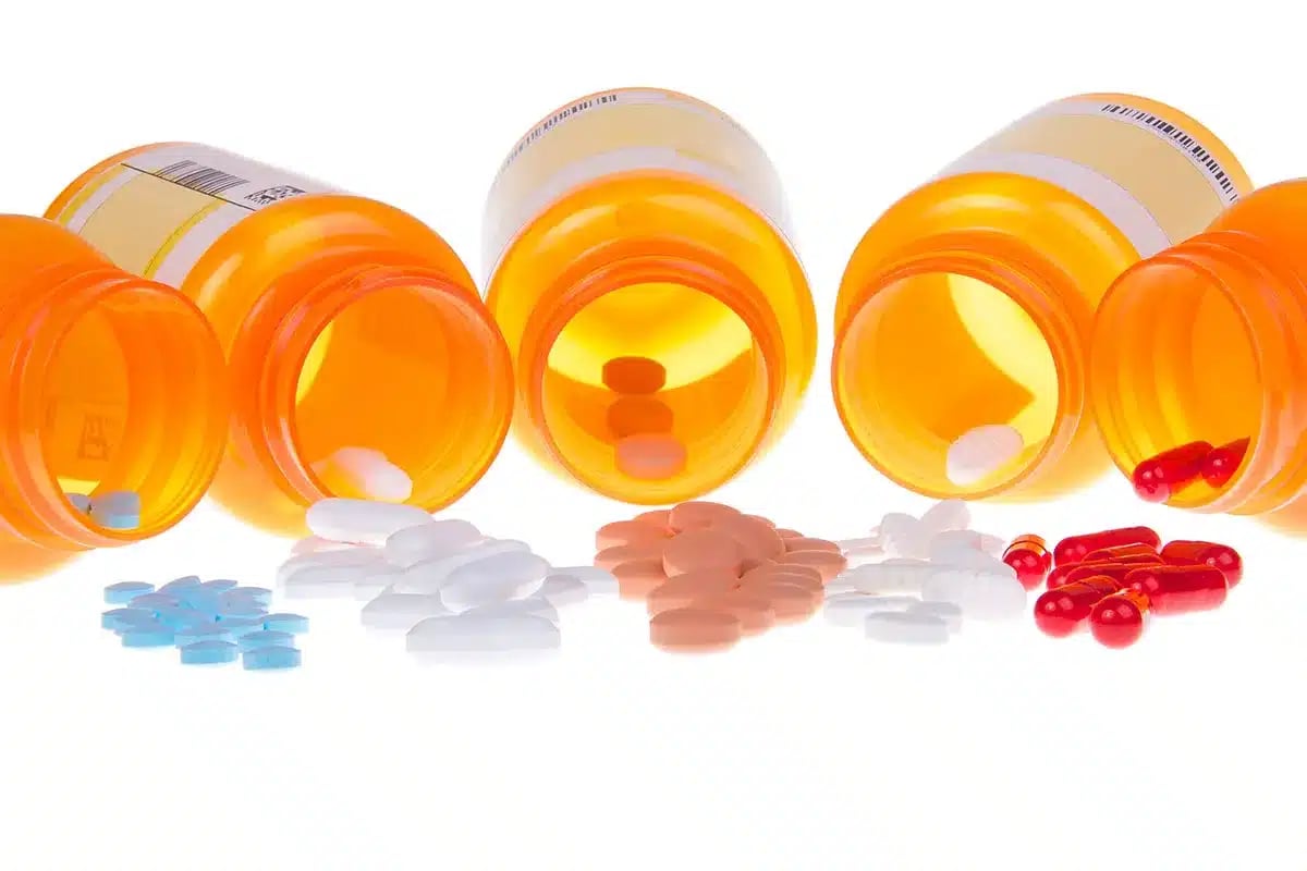 Various pills and capsules spilled from medicine bottles.
