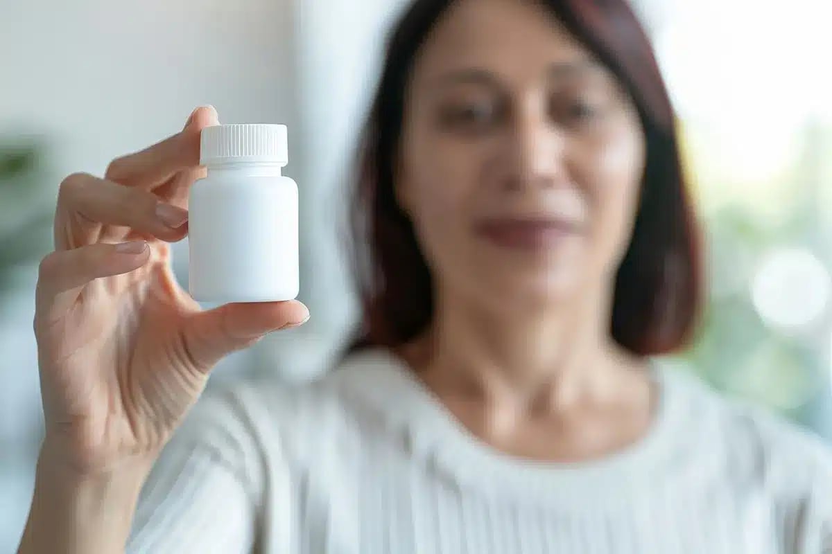 Woman holding small bottle of weight loss pills