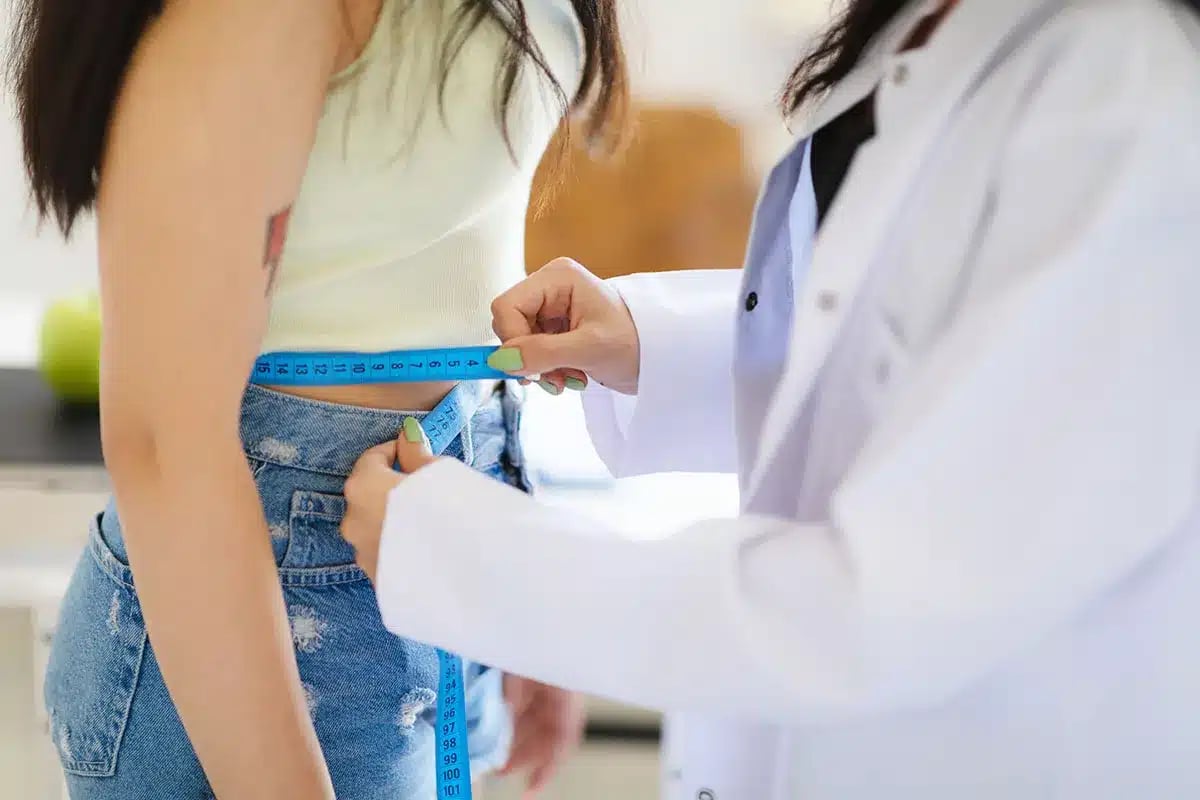 Doctor measuring woman's waist.