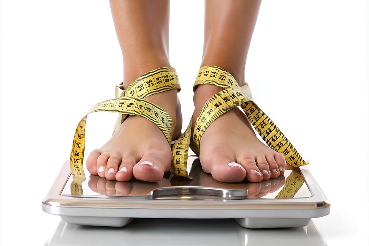 Woman's feet on scale with measuring tape.