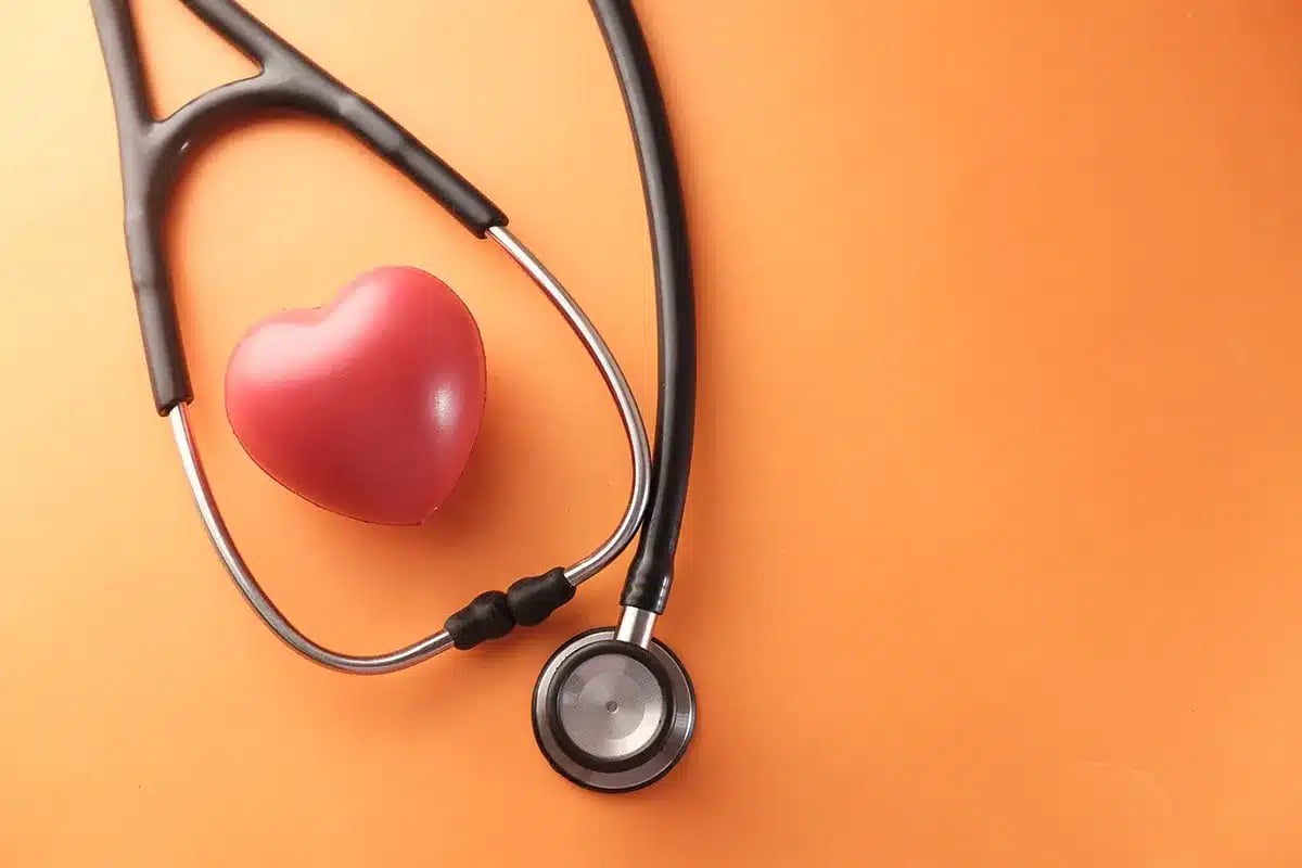 Stethoscope and heart on orange background.