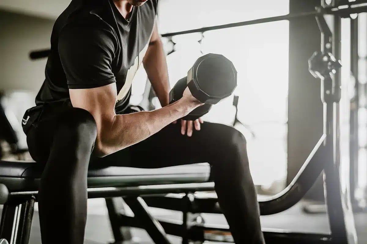 Man doing bicep curls with dumbbells at the gym.