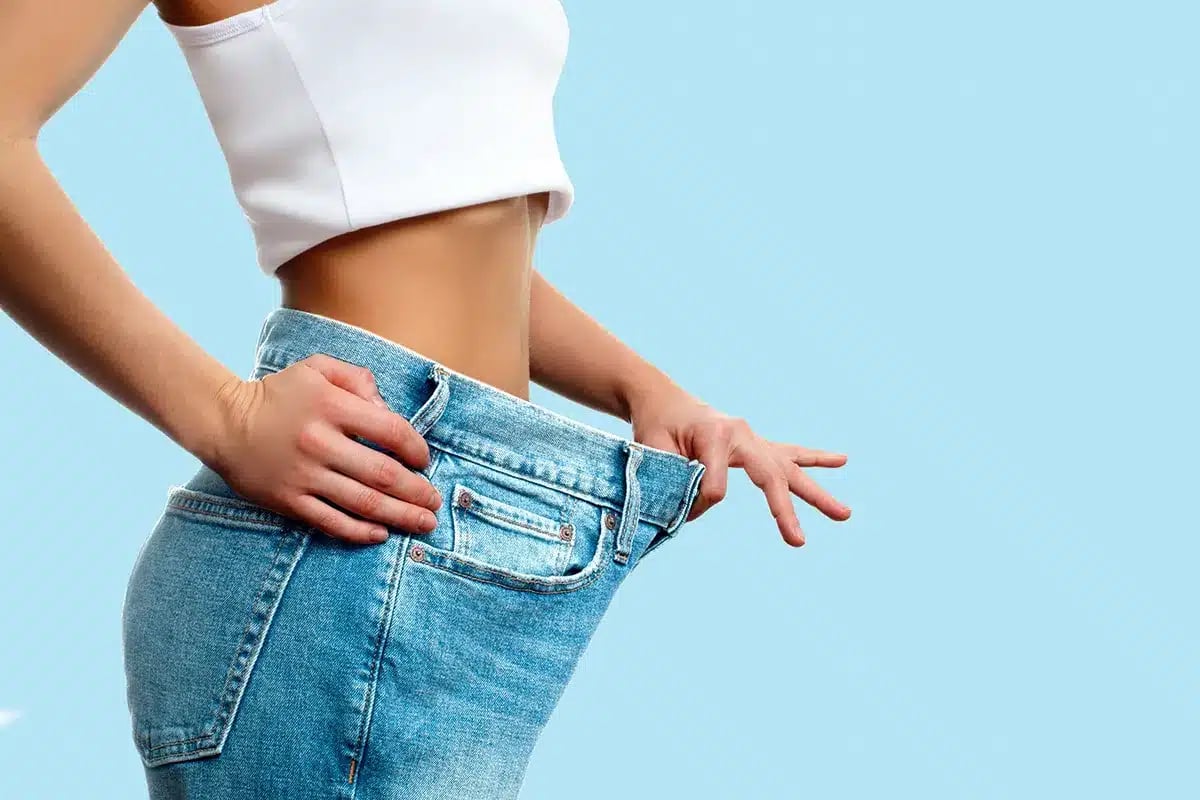 Woman in loose jeans after weight loss.