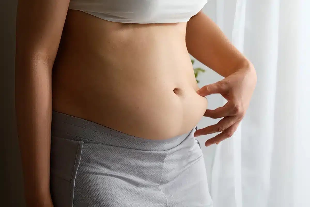 close up of a person pinching excess belly fat