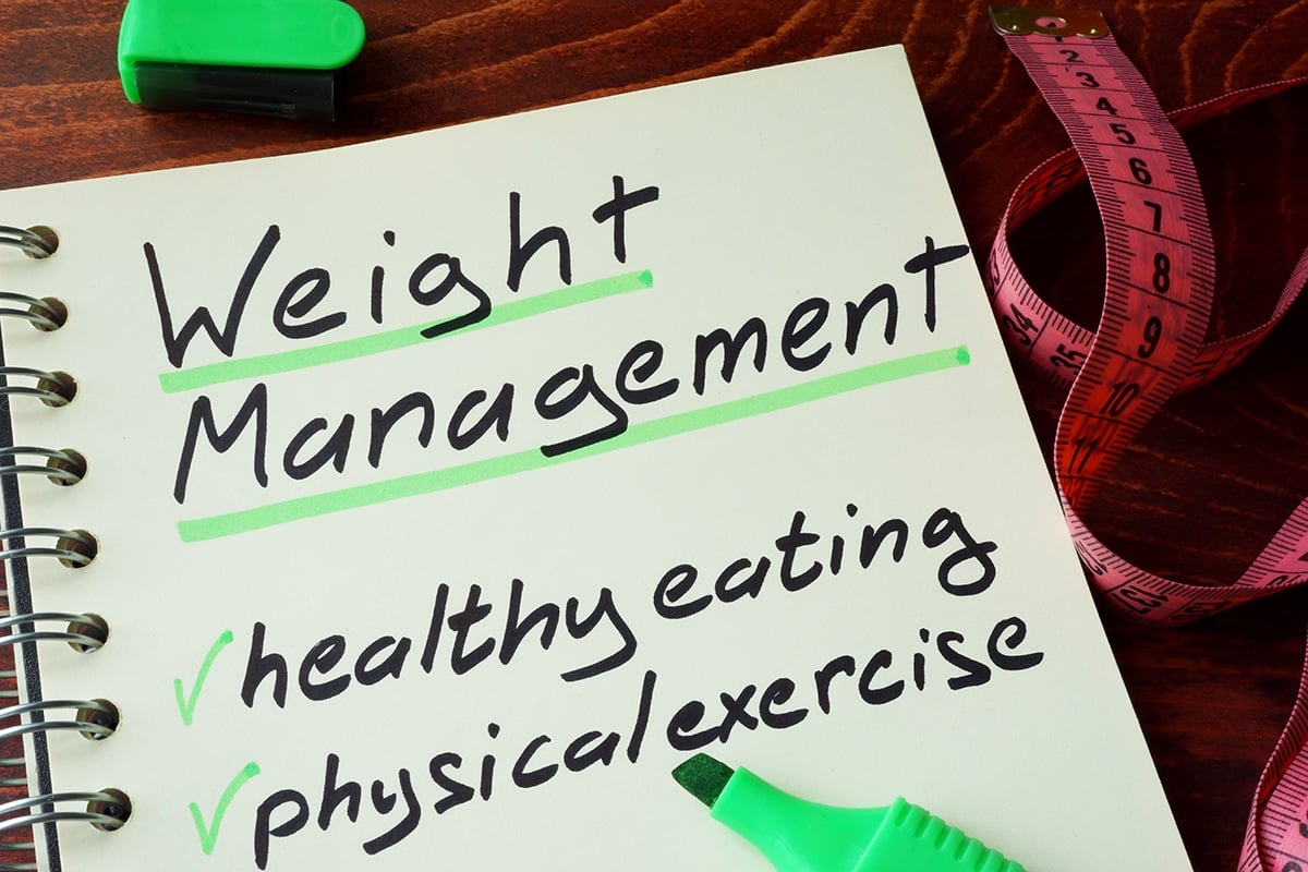 Notepad with sign weight management on a wooden background.