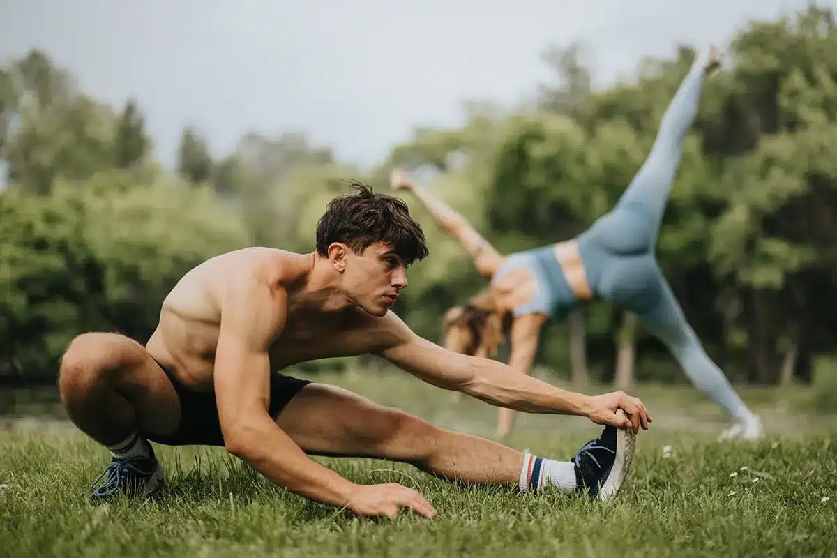 Couple stretching outdoors in park.