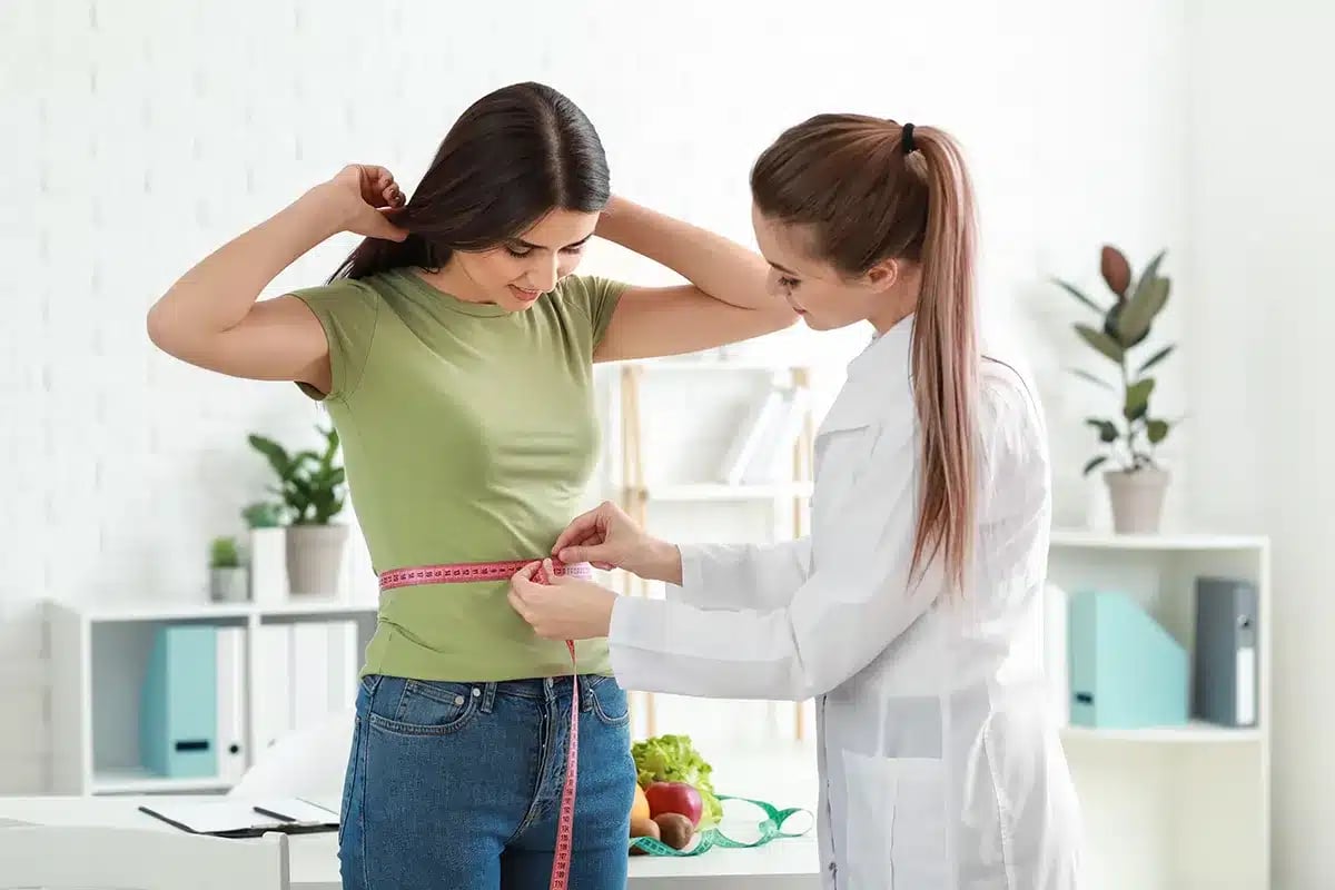 Nutritionist measuring client's waist.
