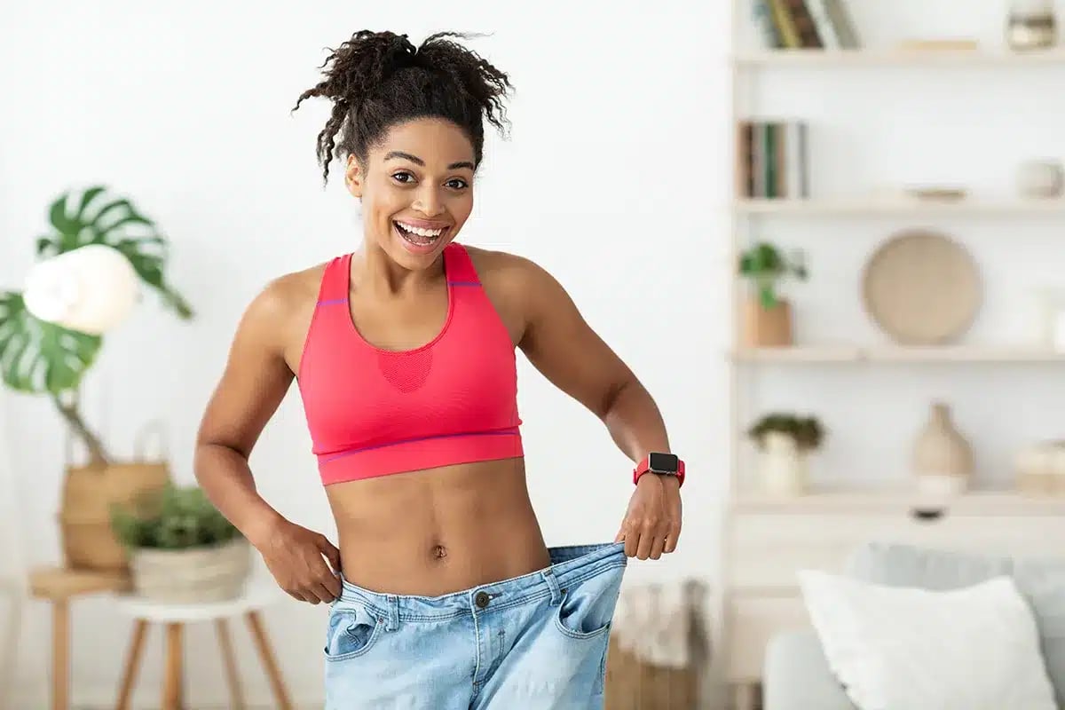 Happy woman in loose jeans after weight loss.