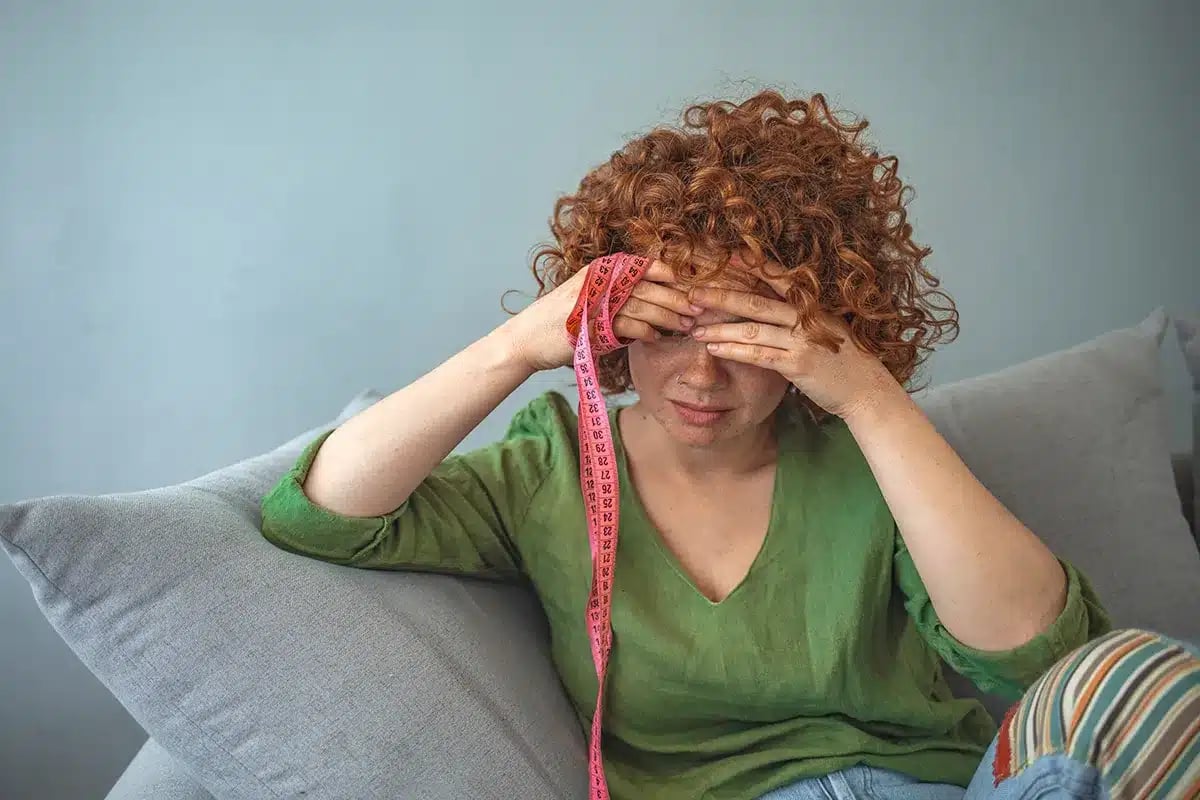 Woman feeling stressed about body image.